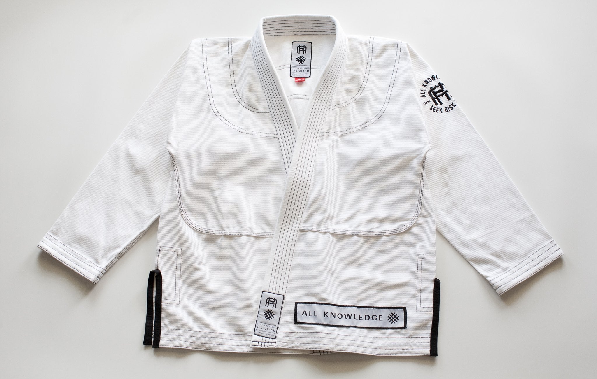 White bjjs uniform with black belt on a light gray background